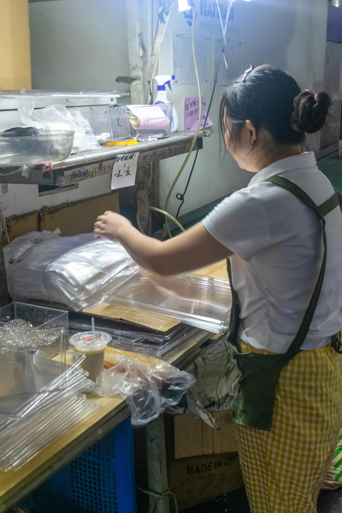 Worker inspecting the edge finish of a clear plastic sheet during quality control